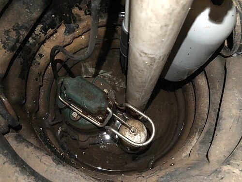 Pompe de relevage installée au fond d'un puisard dans le sol d'une cave