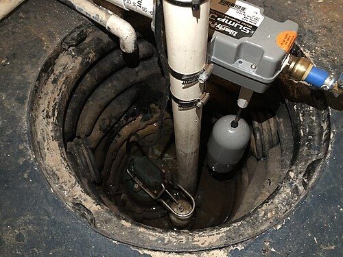 Puisard dans le sol d'une cave avec une pompe de relevage neuve et ses tuyaux